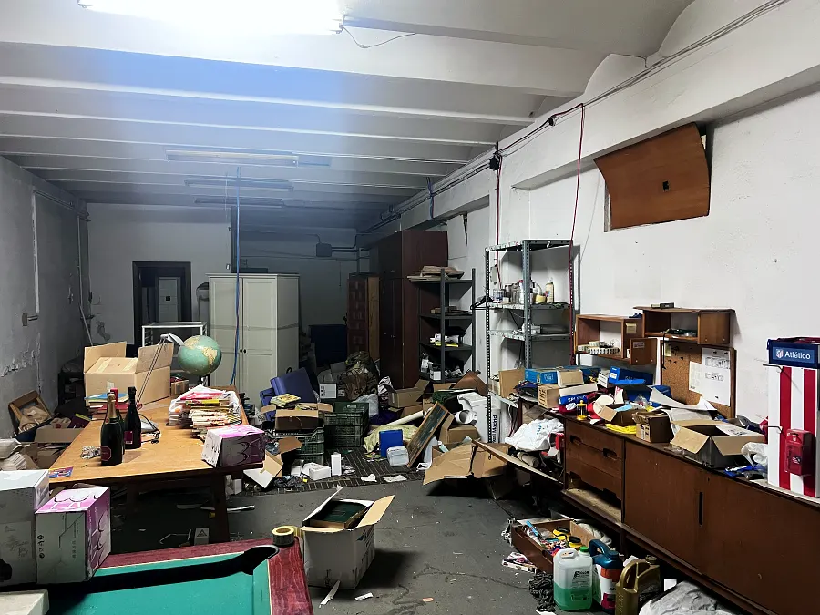 Local con mobiliario de oficina y objetos acumulados antes del vaciado