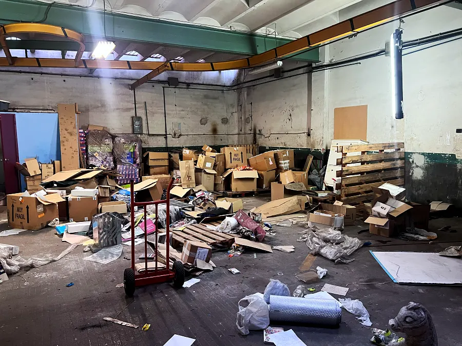 Nave industrial llena de cajas, palés y enseres antes del vaciado